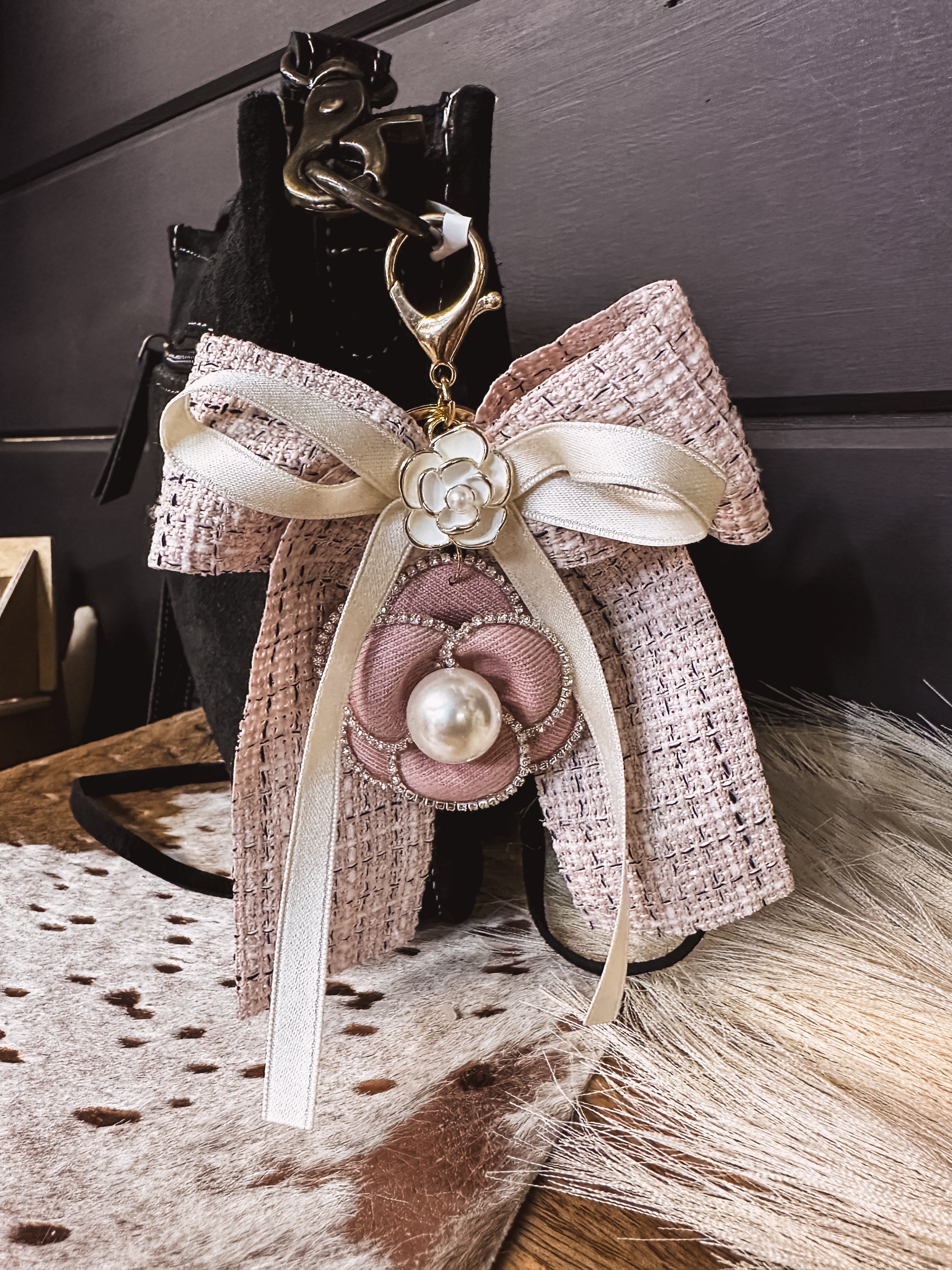 Pink tweed fabric bow and ivory bow keychain with pink and white floral and pearl charms on a lobster claw.