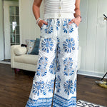 White cotton wide leg pants with denim blue sea inspired print, eyelet cutouts throughout, elastic drawstring waist and pockets with shorts lining.