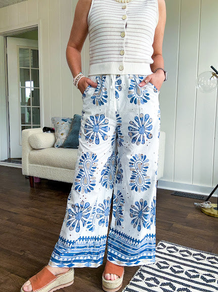 White cotton wide leg pants with denim blue sea inspired print, eyelet cutouts throughout, elastic drawstring waist and pockets with shorts lining.