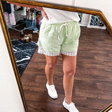 Pistachio green athleisure shorts with under layer trimmed in white lace and overlayer with pockets, elastic drawstring waist.
