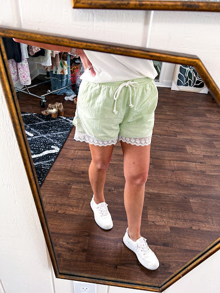 Pistachio green athleisure shorts with under layer trimmed in white lace and overlayer with pockets, elastic drawstring waist.