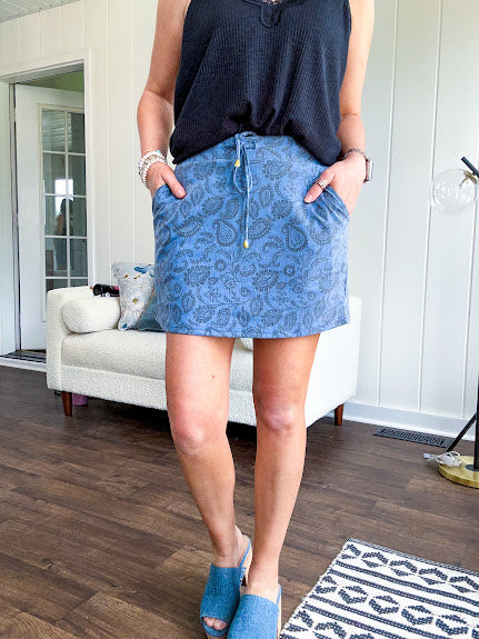 Soft knit denim blue skort with shorts lining, elastic waist and pockets with paisley print throughout.