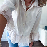 Thin, lightweight beige button down cropped jacket with collar, ruffled hem and ruffle at the cuffs with texture.