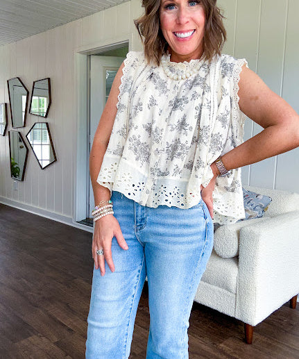 Thin, lightweight oversized cream button down sleeveless blouse with vintage inspired florals throughout and lace inserts and trim at the sleeves and hem.