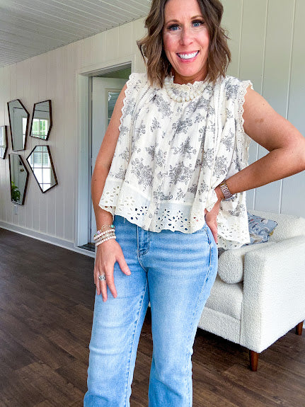 Thin, lightweight oversized cream button down sleeveless blouse with vintage inspired florals throughout and lace inserts and trim at the sleeves and hem.