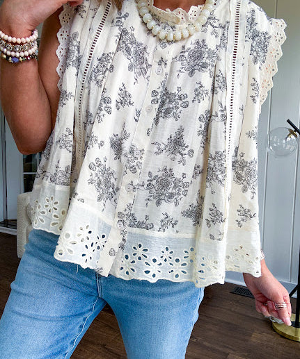 Thin, lightweight oversized cream button down sleeveless blouse with vintage inspired florals throughout and lace inserts and trim at the sleeves and hem.