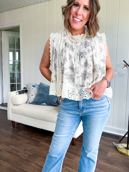 Thin, lightweight oversized cream button down sleeveless blouse with vintage inspired florals throughout and lace inserts and trim at the sleeves and hem.