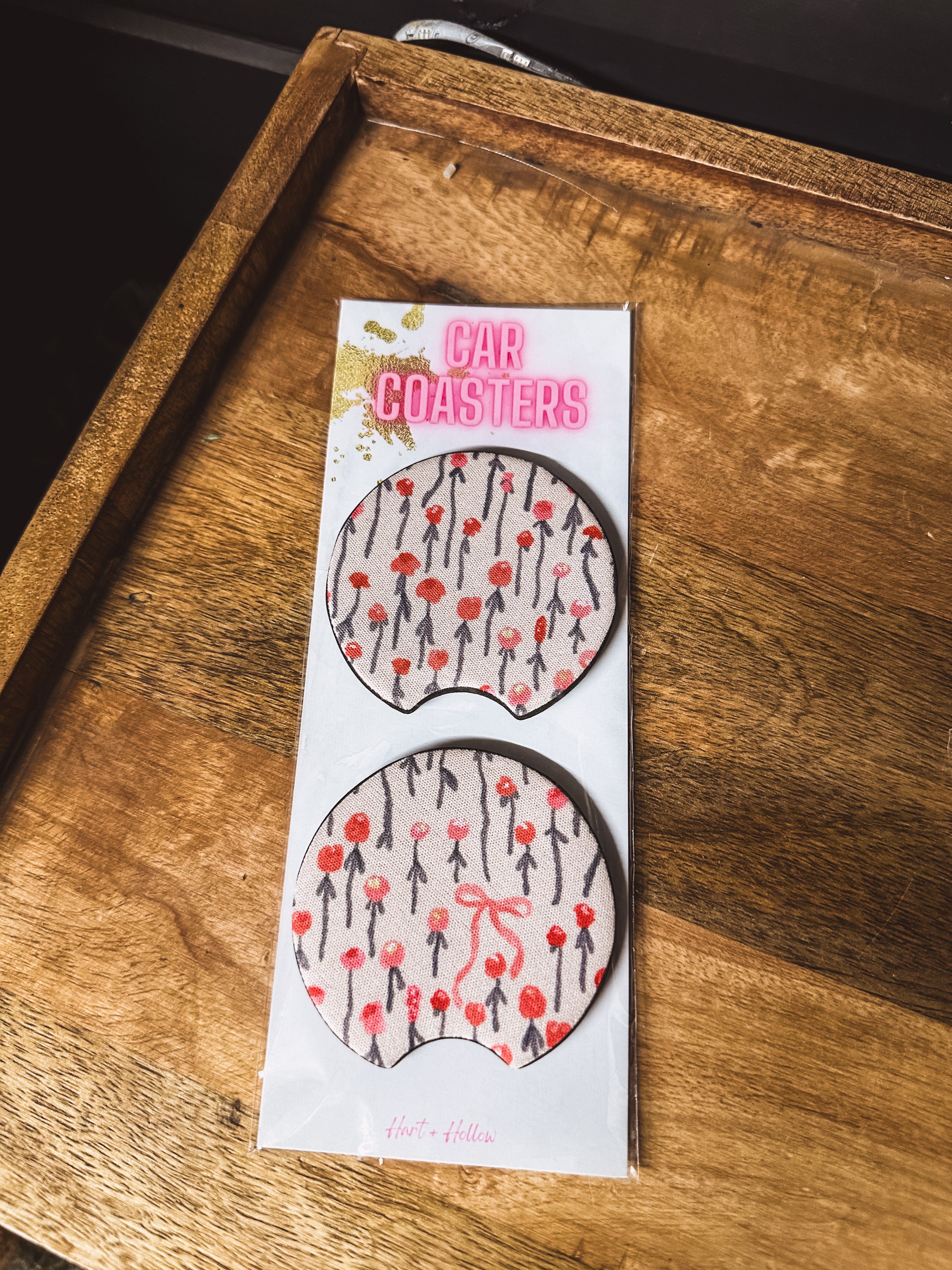 Two cream and red floral/bow neoprene car coasters.
