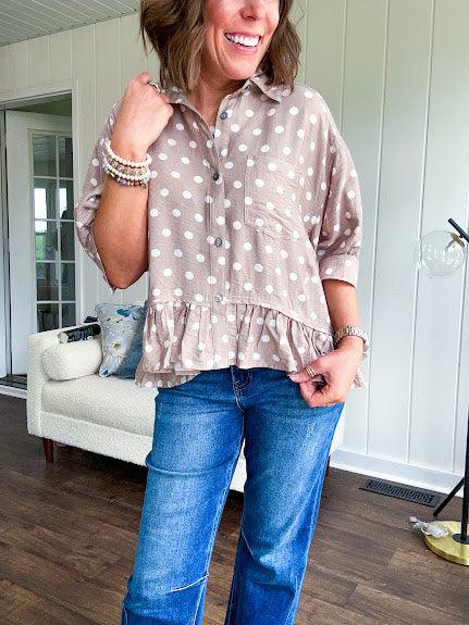 Light, flowy sand colored button down top with collar, 3/4 cuffed sleeves and front pocket with seam detail and ruffled hemline.