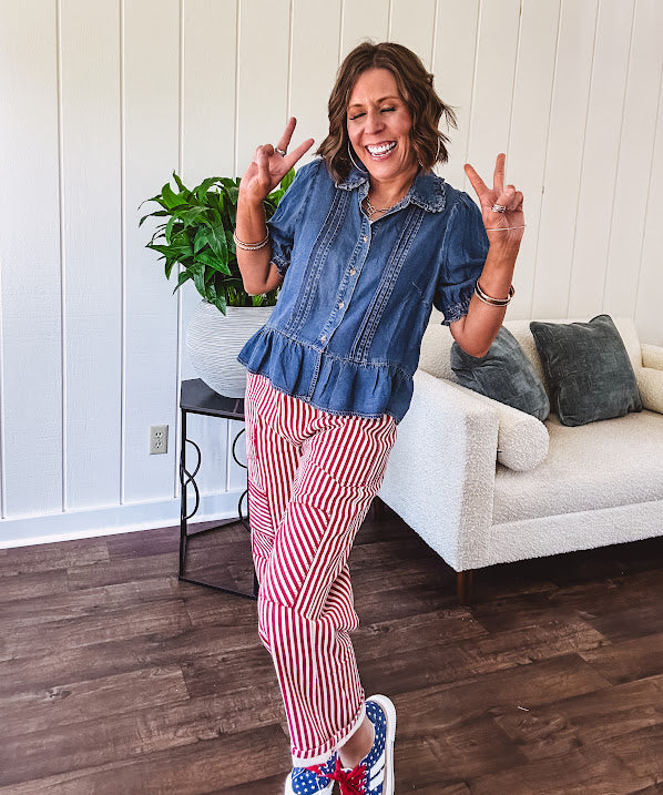 Medium wash Tencel short puffed sleeve top featuring a ruffled collar, button down front, pintuck details down the front and a ruffled hem.