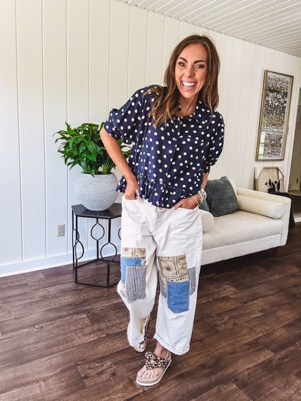 Creamy wide-leg pants, denim-like cotton material with silver grommet belt loops and a coordinating rope belt, button fly and oversized pockets, and striped patchwork in sand, denim, navy, and white creates visual interest down the legs.
