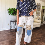 Creamy wide-leg pants, denim-like cotton material with silver grommet belt loops and a coordinating rope belt, button fly and oversized pockets, and striped patchwork in sand, denim, navy, and white creates visual interest down the legs.