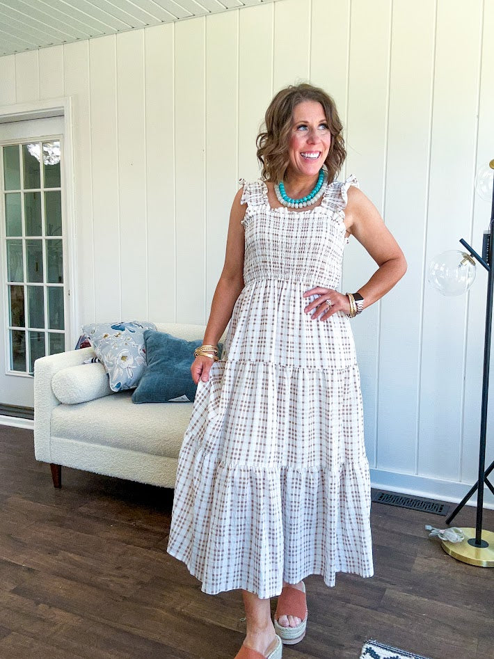 This mocha plaid midi dress is your new summer obsession. The smocked bodice hugs in all the right places while the tiered, flowy skirt does the twirling for you. Ruffled straps and trim add that playful touch that makes heads turn, and the slip lining keeps things cool and comfortable from brunch to sunset.