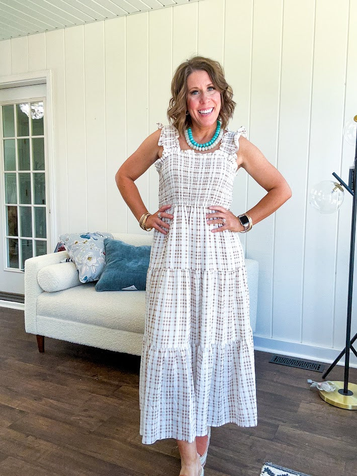 This mocha plaid midi dress is your new summer obsession. The smocked bodice hugs in all the right places while the tiered, flowy skirt does the twirling for you. Ruffled straps and trim add that playful touch that makes heads turn, and the slip lining keeps things cool and comfortable from brunch to sunset.