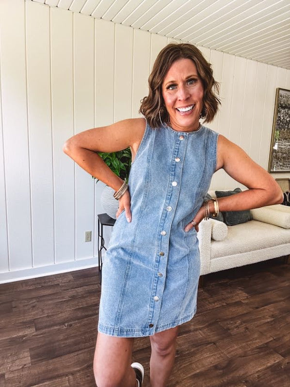Medium wash true denim sleeveless mini dress with silver snap button front and front seams.
