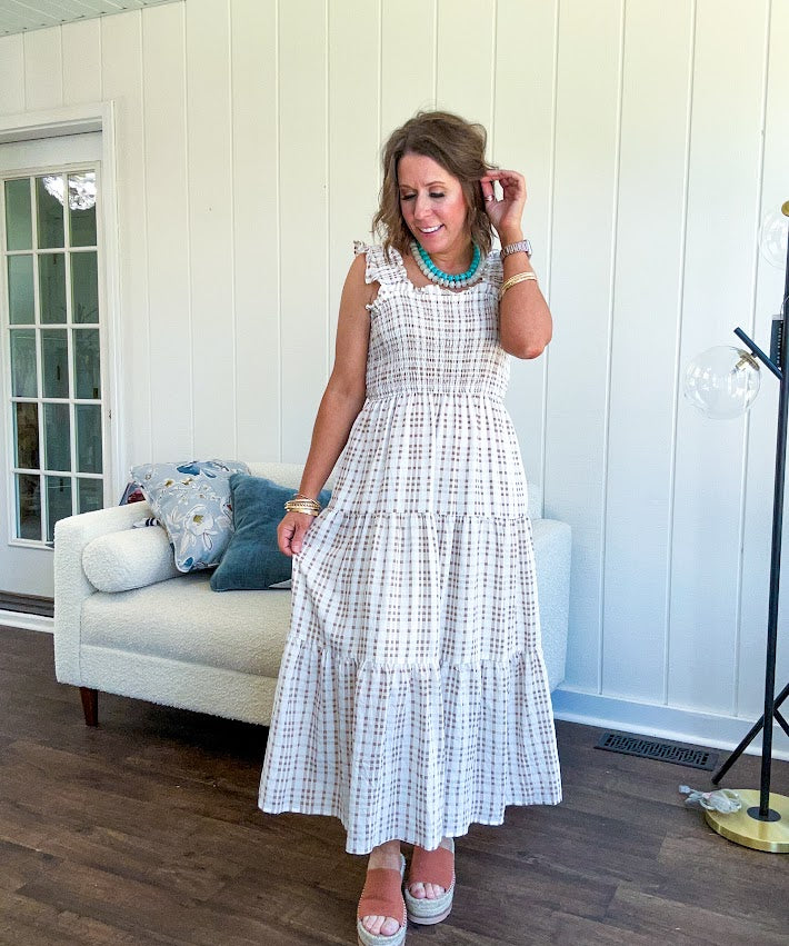 This mocha plaid midi dress is your new summer obsession. The smocked bodice hugs in all the right places while the tiered, flowy skirt does the twirling for you. Ruffled straps and trim add that playful touch that makes heads turn, and the slip lining keeps things cool and comfortable from brunch to sunset.