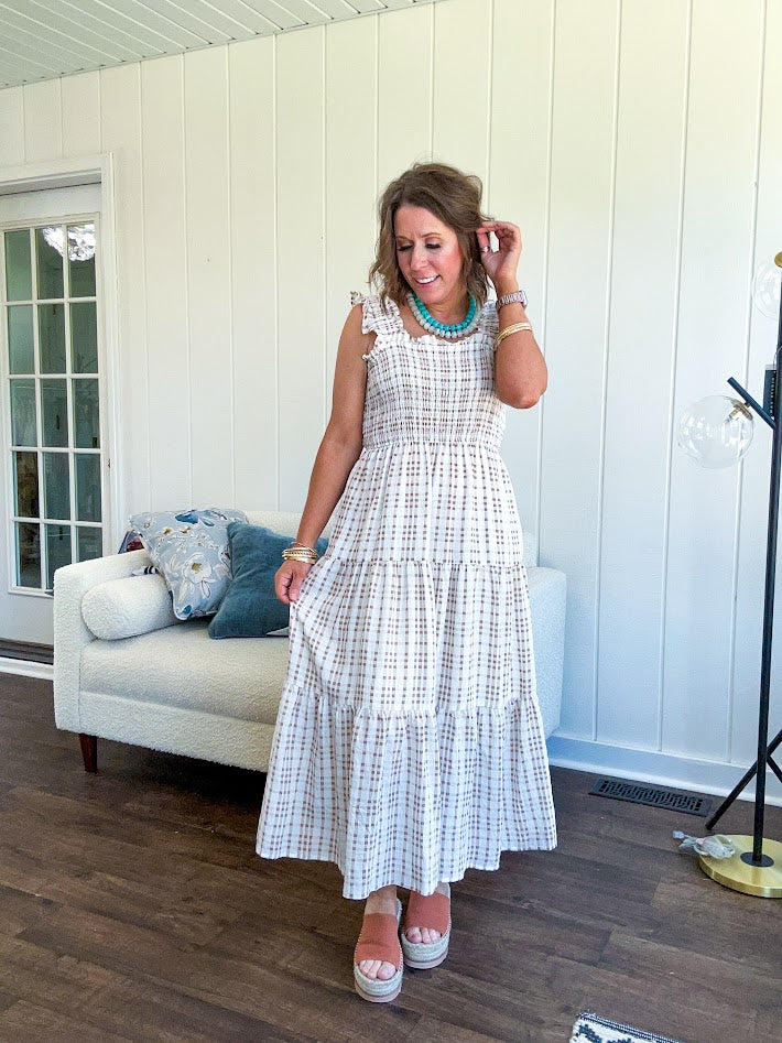 This mocha plaid midi dress is your new summer obsession. The smocked bodice hugs in all the right places while the tiered, flowy skirt does the twirling for you. Ruffled straps and trim add that playful touch that makes heads turn, and the slip lining keeps things cool and comfortable from brunch to sunset.