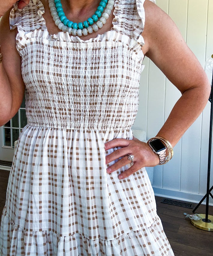 This mocha plaid midi dress is your new summer obsession. The smocked bodice hugs in all the right places while the tiered, flowy skirt does the twirling for you. Ruffled straps and trim add that playful touch that makes heads turn, and the slip lining keeps things cool and comfortable from brunch to sunset.