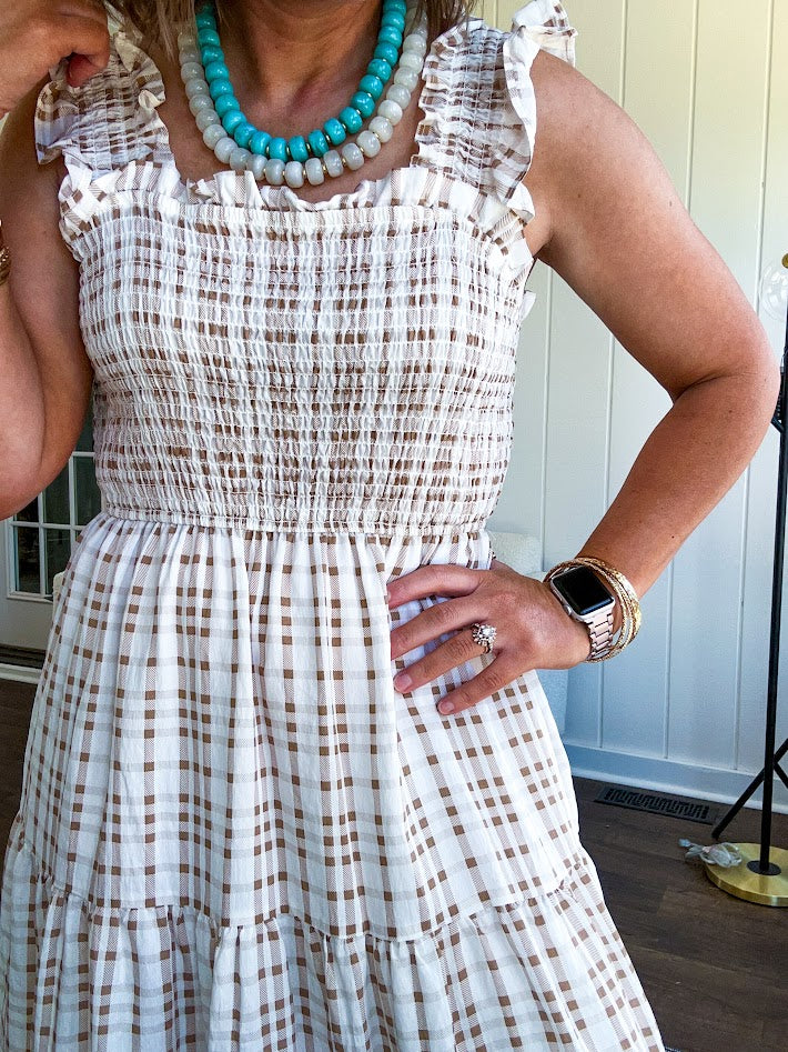 This mocha plaid midi dress is your new summer obsession. The smocked bodice hugs in all the right places while the tiered, flowy skirt does the twirling for you. Ruffled straps and trim add that playful touch that makes heads turn, and the slip lining keeps things cool and comfortable from brunch to sunset.
