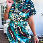 Welcome to the jungle in this bold rainforest-inspired print romper that commands attention. Crafted in rich earth tones, it features a button down front and two buttoned front pockets, a classic collar, and a matching fabric belt that cinches your silhouette. The relaxed design flows effortlessly, and yes—it has pockets