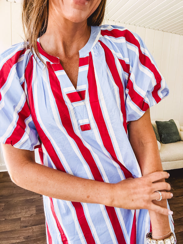Light blue, white and red striped mini dress featuring a V neck and mock collar, puffed sleeves and pockets.