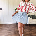 Light wash Tencel mini skirt with partial metal button down front with pleats and elastic drawstring waist.