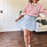 Light wash Tencel mini skirt with partial metal button down front with pleats and elastic drawstring waist.