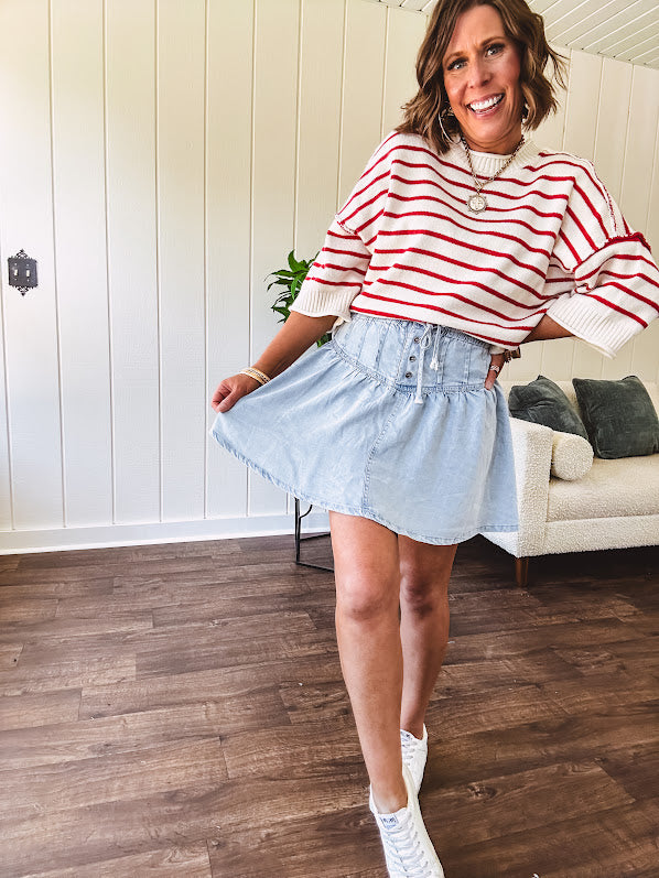 Light wash Tencel mini skirt with partial metal button down front with pleats and elastic drawstring waist.