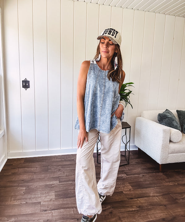 Stretchy medium washed denim tank with canvas adjustable straps at the shoulders and a wide hem with vertical seams throughout.
