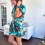 Welcome to the jungle in this bold rainforest-inspired print romper that commands attention. Crafted in rich earth tones, it features a button down front and two buttoned front pockets, a classic collar, and a matching fabric belt that cinches your silhouette. The relaxed design flows effortlessly, and yes—it has pockets