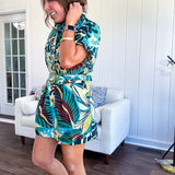 Welcome to the jungle in this bold rainforest-inspired print romper that commands attention. Crafted in rich earth tones, it features a button down front and two buttoned front pockets, a classic collar, and a matching fabric belt that cinches your silhouette. The relaxed design flows effortlessly, and yes—it has pockets