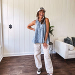Stretchy medium washed denim tank with canvas adjustable straps at the shoulders and a wide hem with vertical seams throughout.