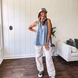 Stretchy medium washed denim tank with canvas adjustable straps at the shoulders and a wide hem with vertical seams throughout.