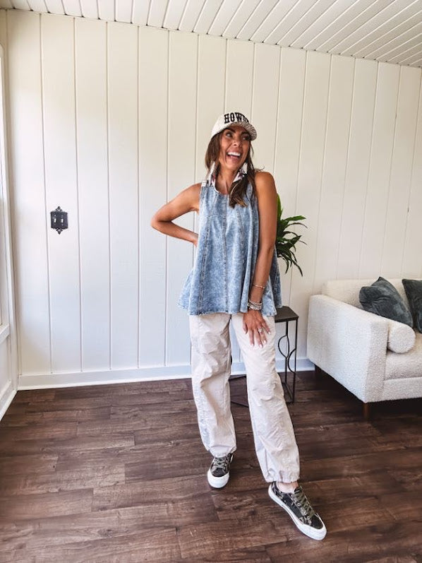 Stretchy medium washed denim tank with canvas adjustable straps at the shoulders and a wide hem with vertical seams throughout.