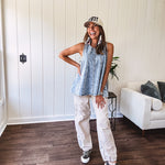 Stretchy medium washed denim tank with canvas adjustable straps at the shoulders and a wide hem with vertical seams throughout.