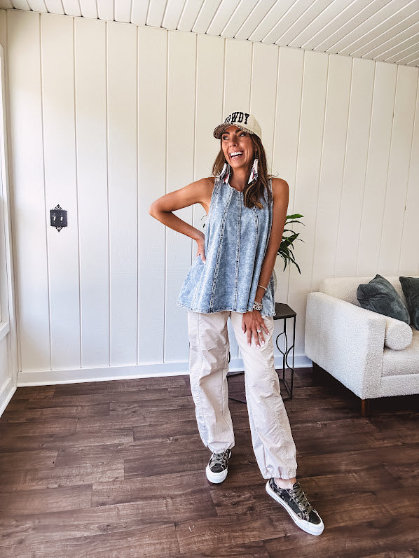 Stretchy medium washed denim tank with canvas adjustable straps at the shoulders and a wide hem with vertical seams throughout.