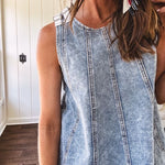 Stretchy medium washed denim tank with canvas adjustable straps at the shoulders and a wide hem with vertical seams throughout.