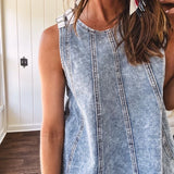 Stretchy medium washed denim tank with canvas adjustable straps at the shoulders and a wide hem with vertical seams throughout.
