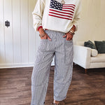 Cream long sleeved sweater with round neck and red trim at neck an cuffs with American Flag motif.