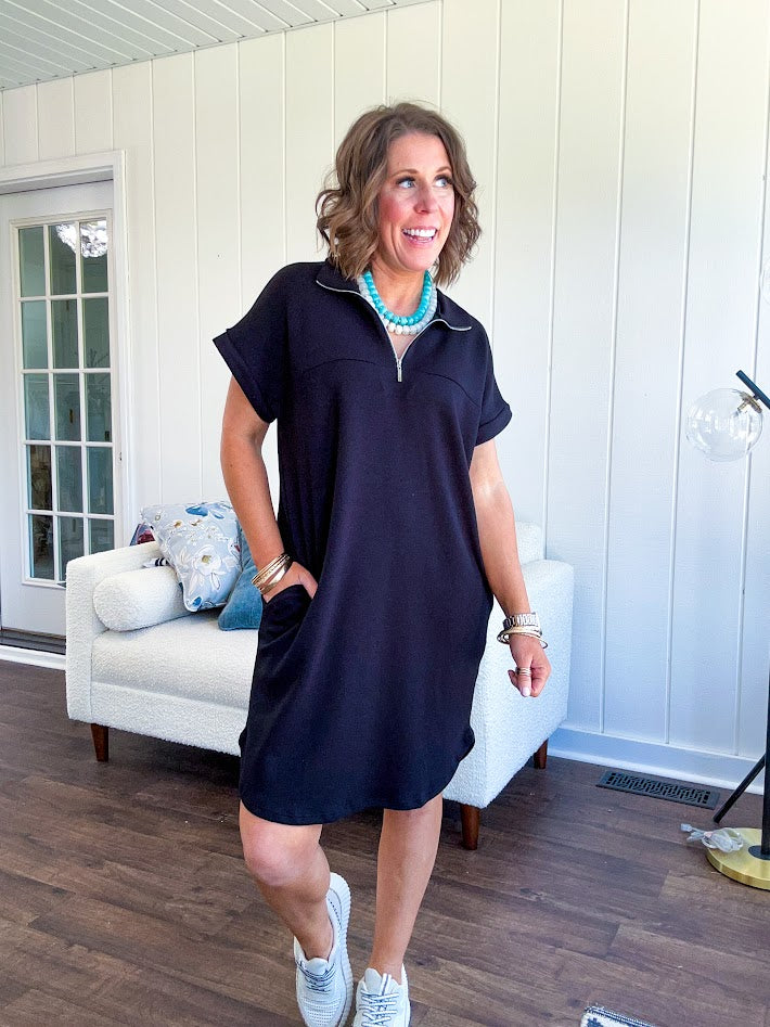 The scoop hem is a flattering fit that is sure to be the star of the show. This black 1/4 zip dress combines comfort with contemporary style, featuring a distinctive scoop hem that creates an elegant silhouette.