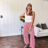 Thin, stretchy red and white checkered barrel pants with button and zipper closure.