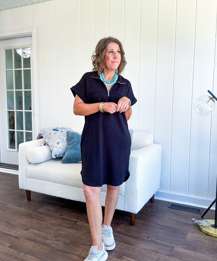 The scoop hem is a flattering fit that is sure to be the star of the show. This black 1/4 zip dress combines comfort with contemporary style, featuring a distinctive scoop hem that creates an elegant silhouette.