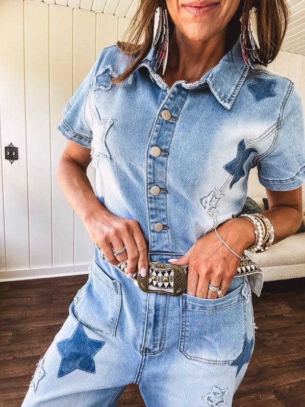 Light wash denim jumpsuit with button front, collar and star patches throughout with front and back pockets. Wide leg design.