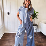 Soft terry-like cotton jumpsuit in indigo and light blue stripes with star patches throughout with lace embellishments. Wide lg design and faux wooden buttons down the front.