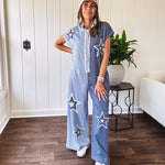 Soft terry-like cotton jumpsuit in indigo and light blue stripes with star patches throughout with lace embellishments. Wide lg design and faux wooden buttons down the front.