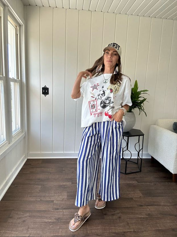 White oversized tee featuring a mixed print of black, red and cream in western, leo and playing card theme.