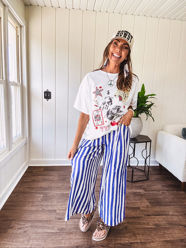 White oversized tee featuring a mixed print of black, red and cream in western, leo and playing card theme.