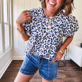 Thin, lightweight flowy puff sleeve blouse with pintuck detail at the yoke and shades of blue leopard print throughout.