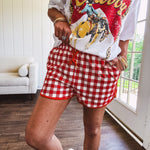 Thin, lightweight orange/red gingham athleisure shorts with elastic drawstring waist, pockets and matching trim.