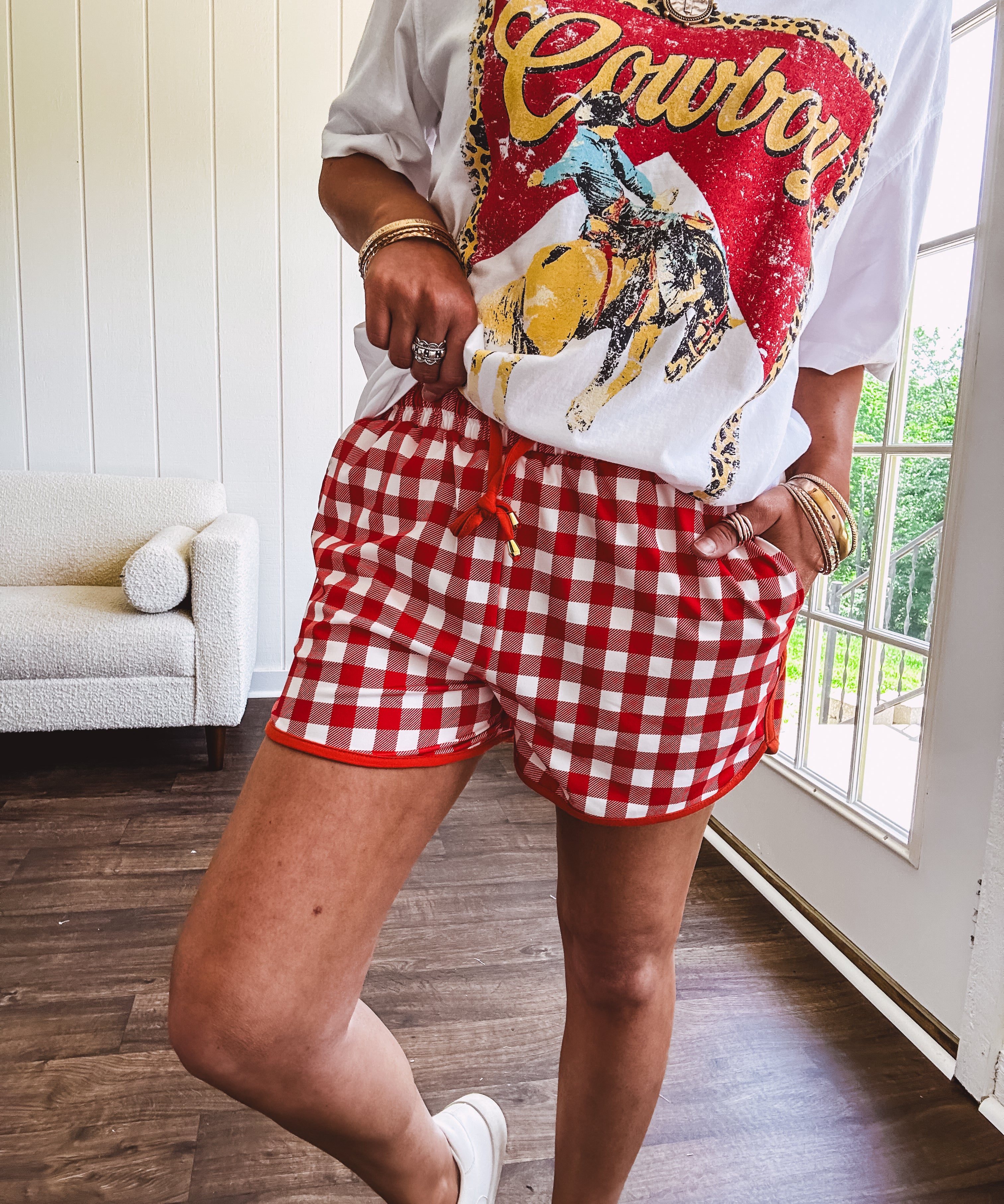 Thin, lightweight orange/red gingham athleisure shorts with elastic drawstring waist, pockets and matching trim.